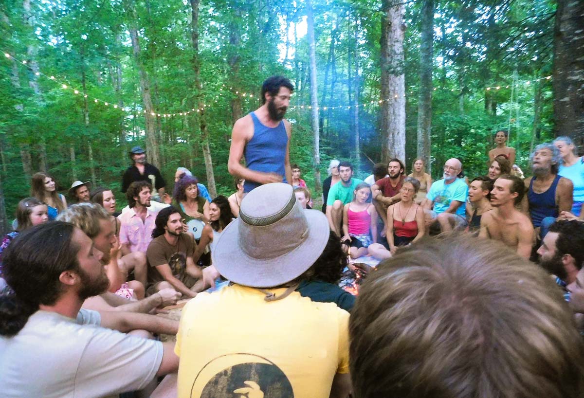 Josh Fox Standing in Center of Circle of People in the Woods Performing a Grief Ceremony