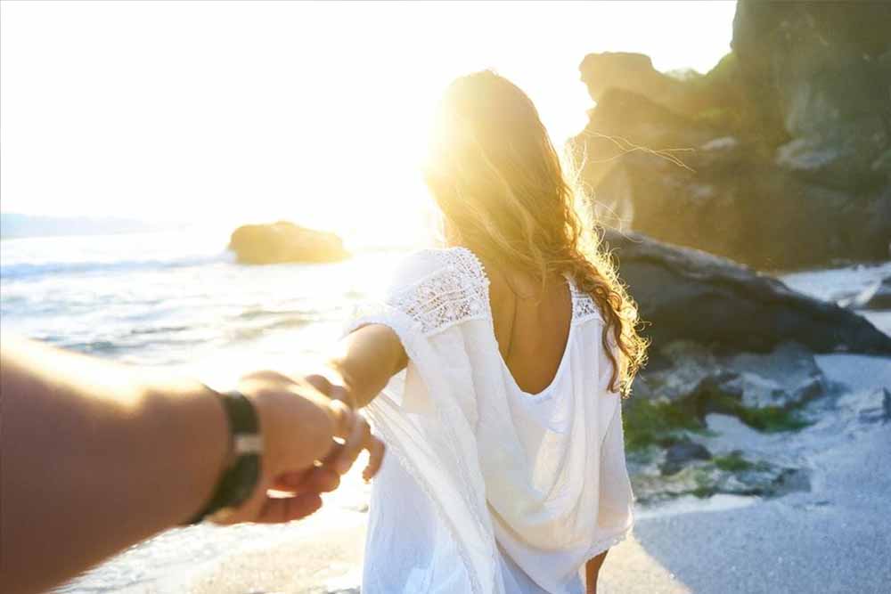 Woman leading man onto beach during sunset into sensual experience to simple technique to last longer in bed tonight and prevent premature ejaculation