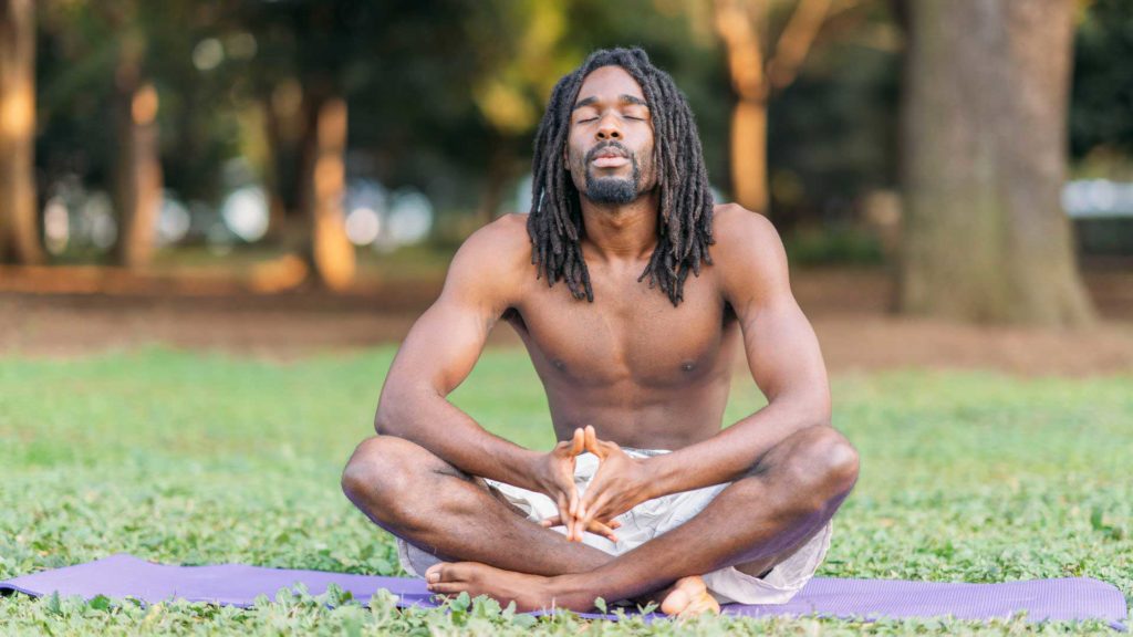 Man Meditating on a Yoga Mat in a Park