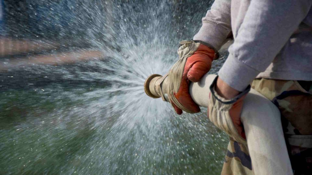 Man holding a fire hose that is supposed to represent ejaculation.