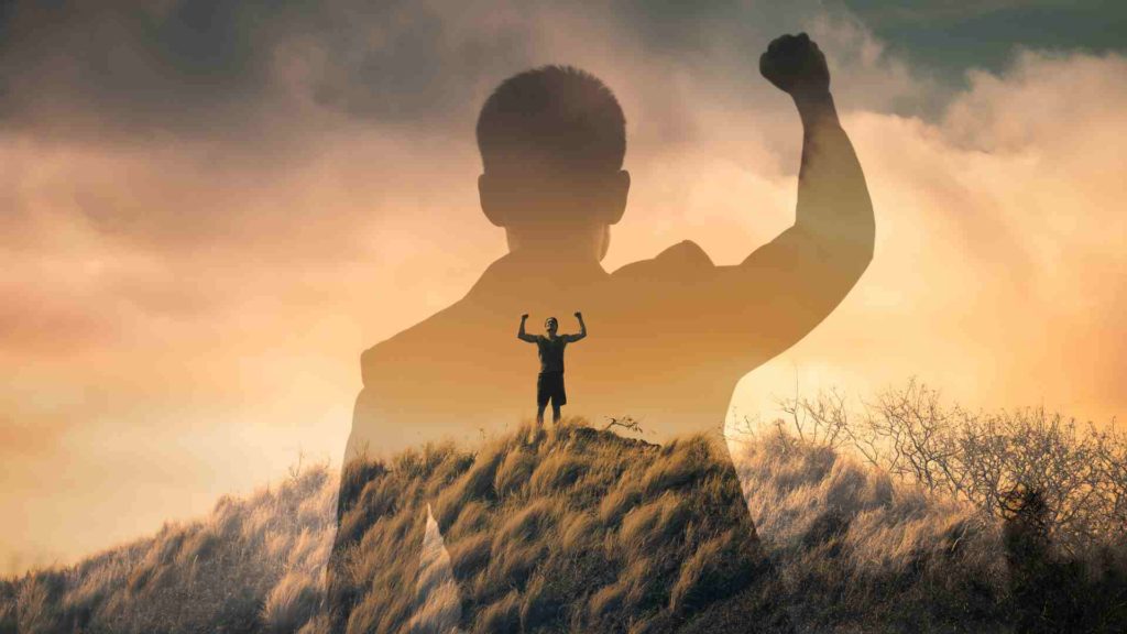 Image of a man on a hill raising his arms in success from practicing semen retention.