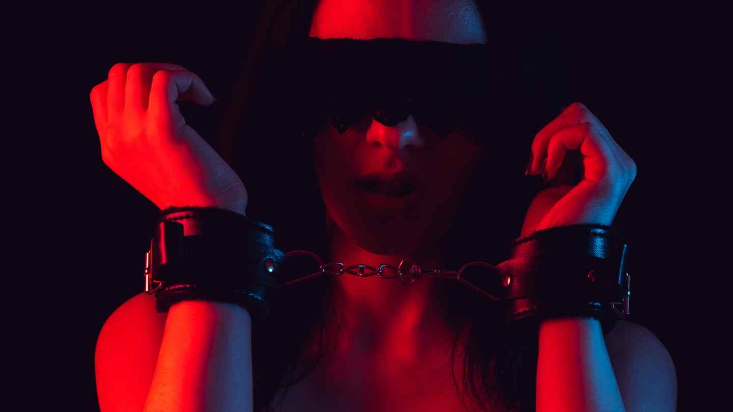 Photo of a woman in handcuffs with a blindfold showing bondage and sensory deprivation play in BDSM.