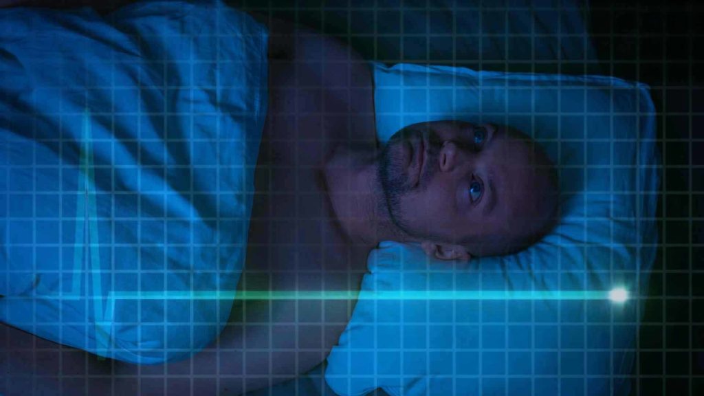 Image of man laying on bed at night stressed with a flatline graphic over his body to represent nofap flatline.